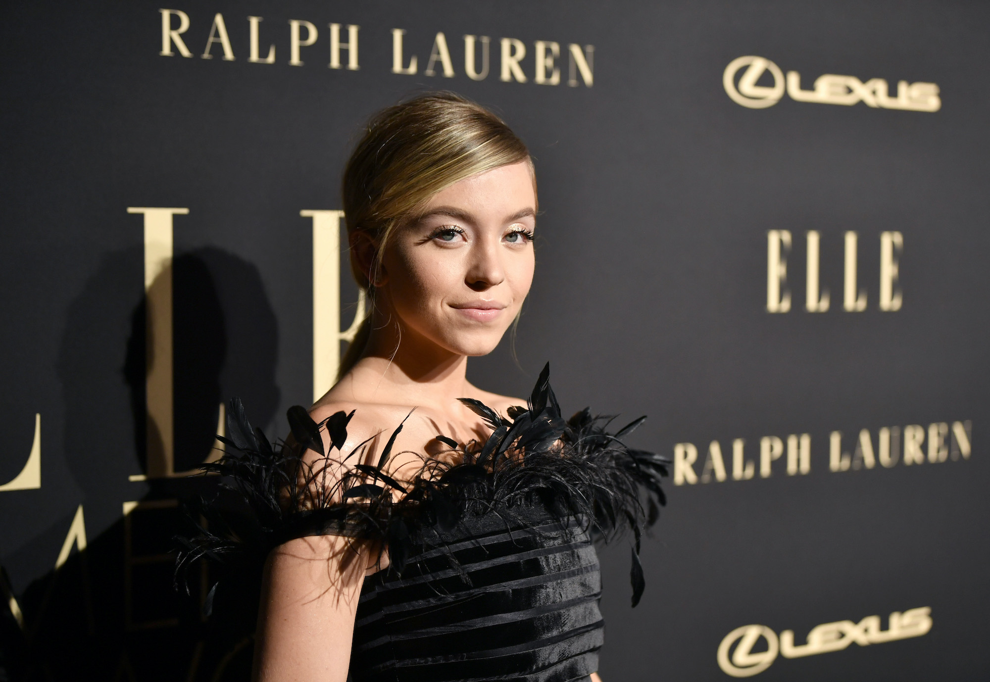 Sydney Sweeney smiling in front of a black background