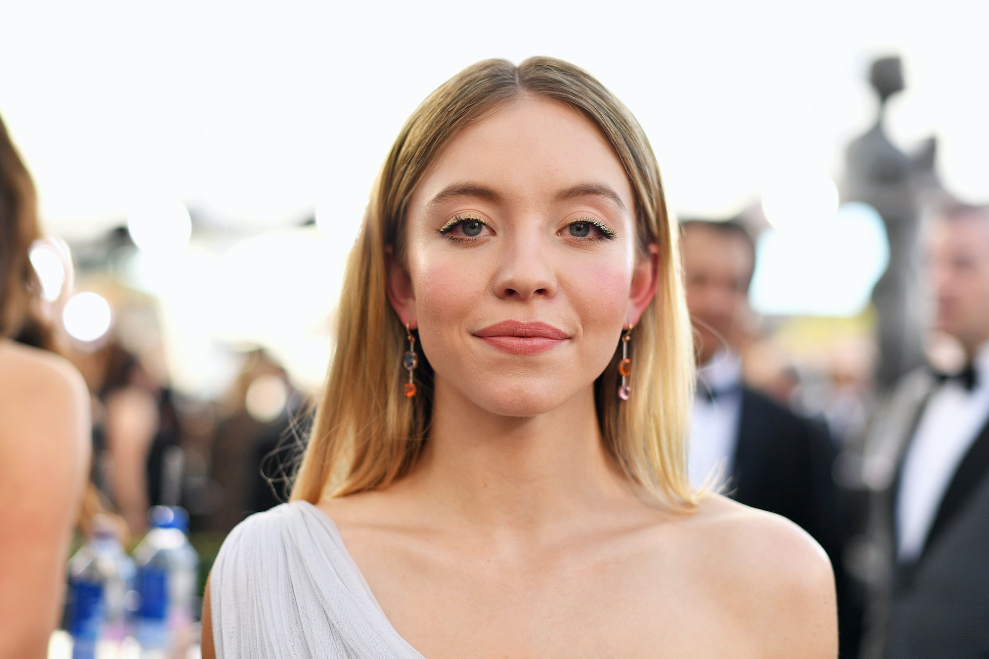 Sydney Sweeney smiling in front of a blurred crowd