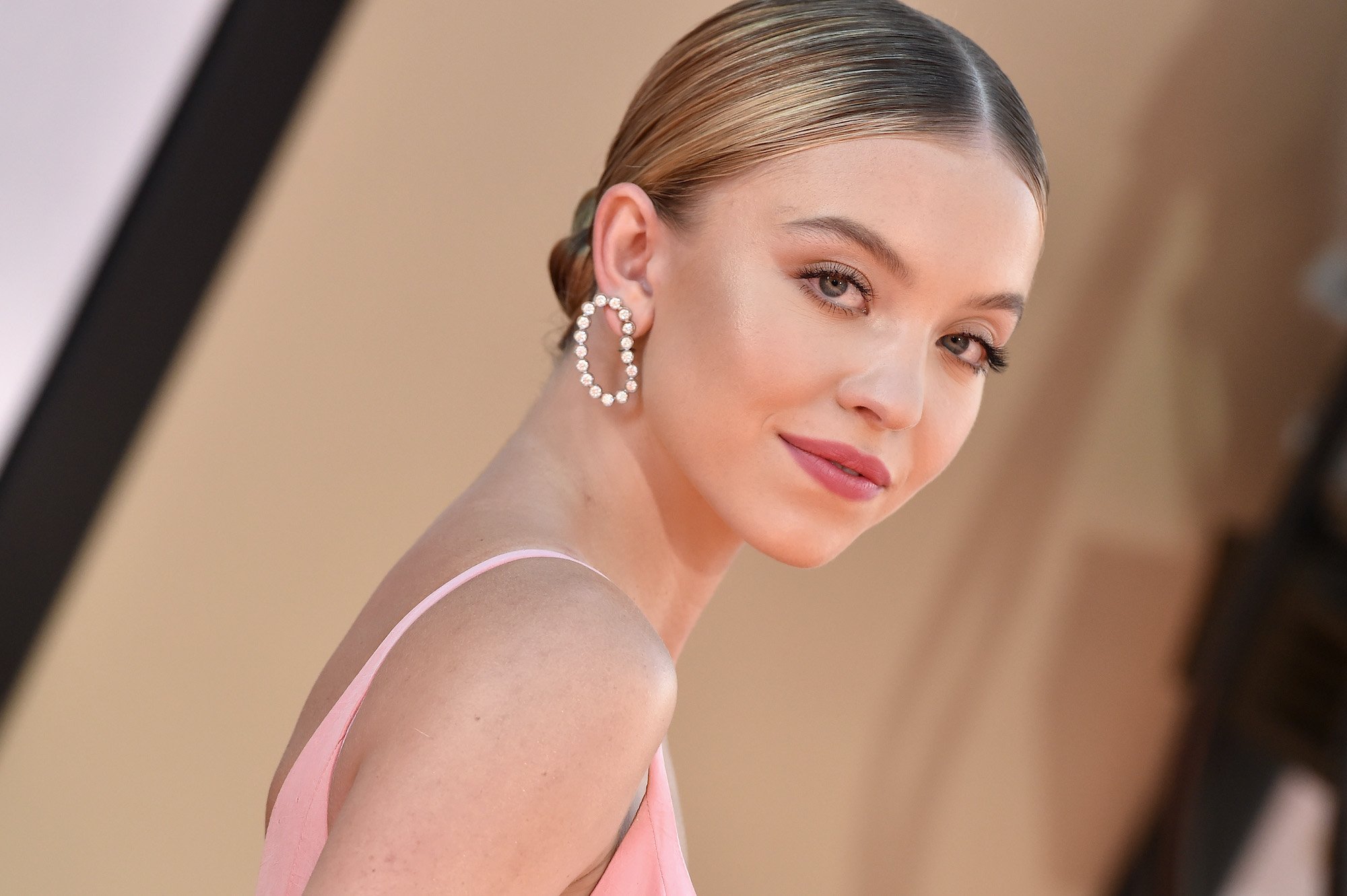 Sydney Sweeney smiling in front of a blurred background