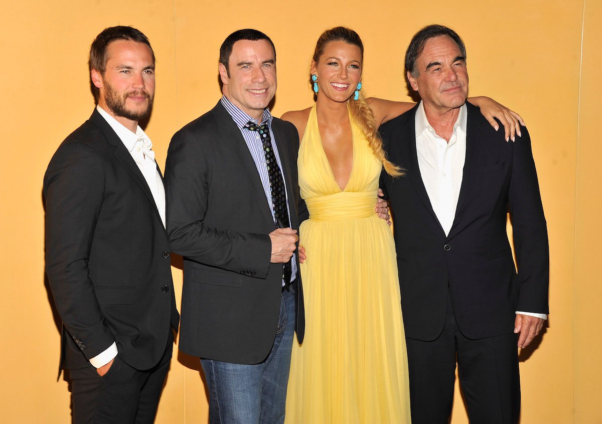 Taylor Kitsch, John Travolta, Blake Lively, and Oliver Stone smile as they pose together for cameras at the New York City premiere of 'Savages' in 2012