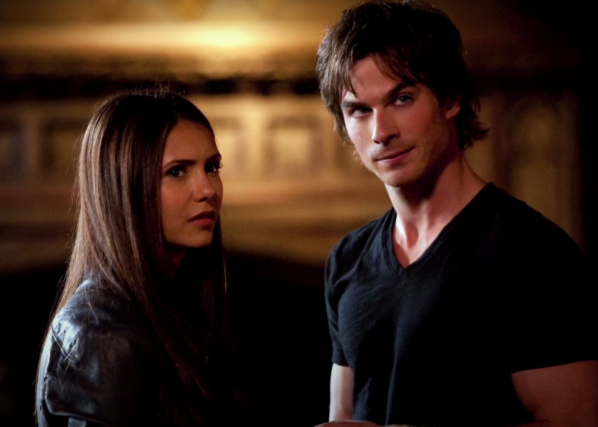 Elena and Damon in 'The Vampire Diaries' stand in front of a fireplace
