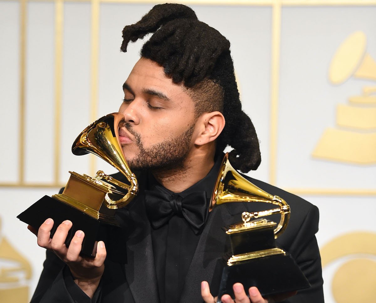 The Weeknd holding his 2 Grammy awards and kissing one at the 2016 Grammys | Steve Granitz/WireImage