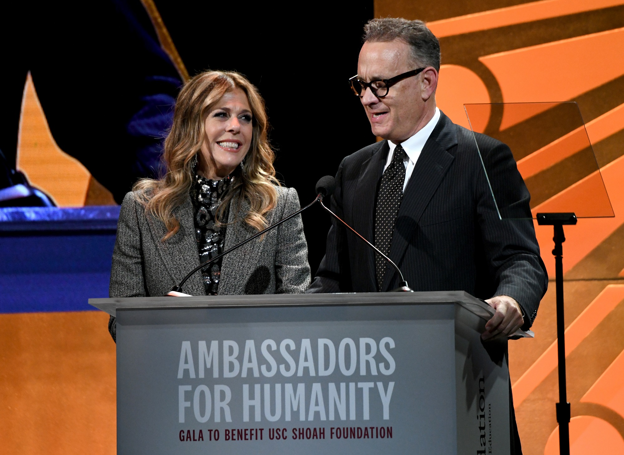 Rita Wilson and Tom Hanks speak at a podium together