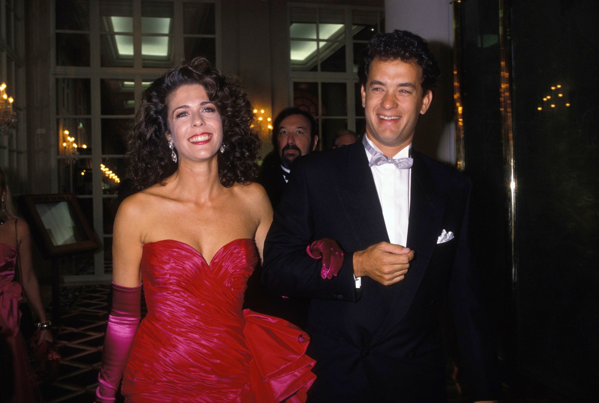 Tom Hanks's wife, Rita Wilson wearig a red dress while Hanks is in a tux
