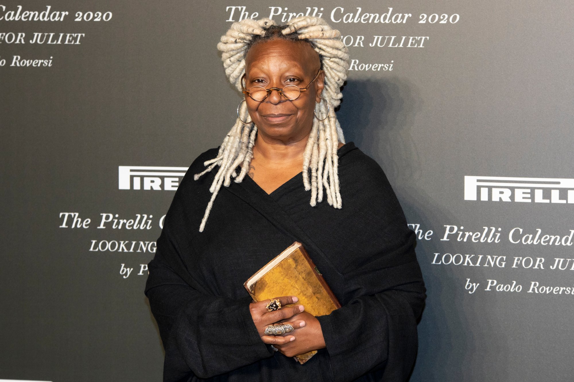 The View star Whoopi Goldberg smiling in front of a black background