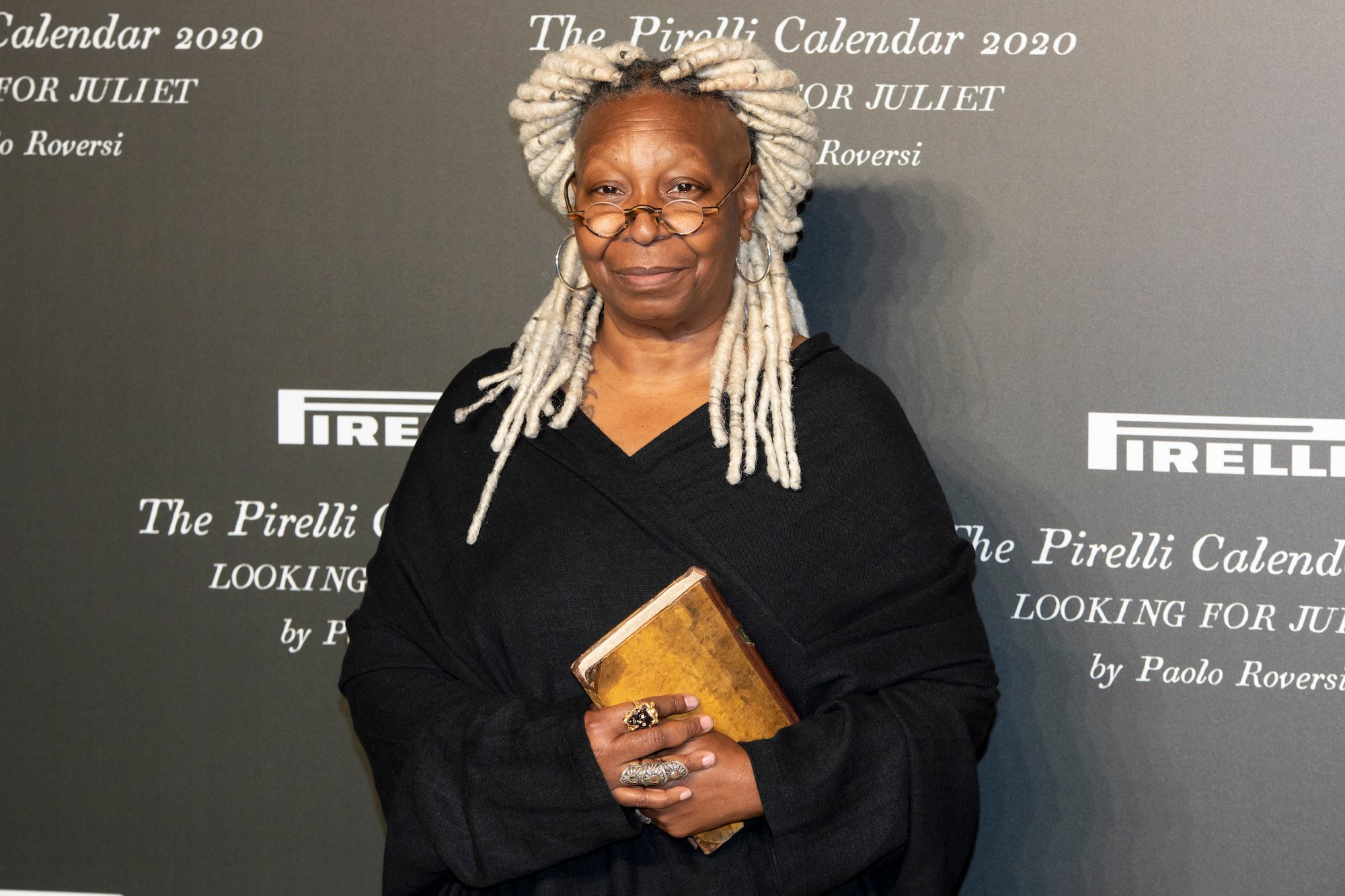 The View star Whoopi Goldberg smiling in front of a black background