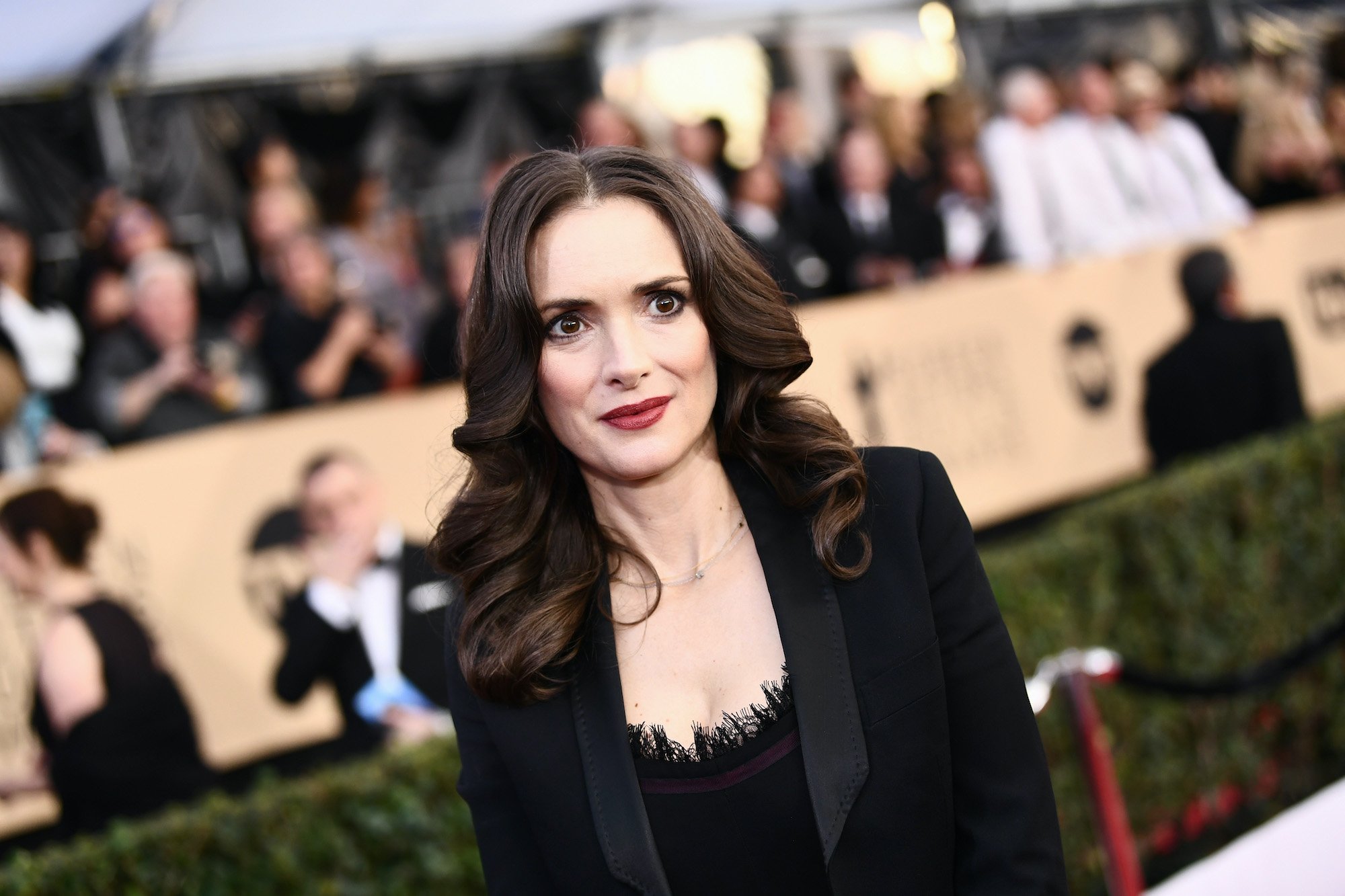 Winona Ryder smiling in front of a blurred crowd