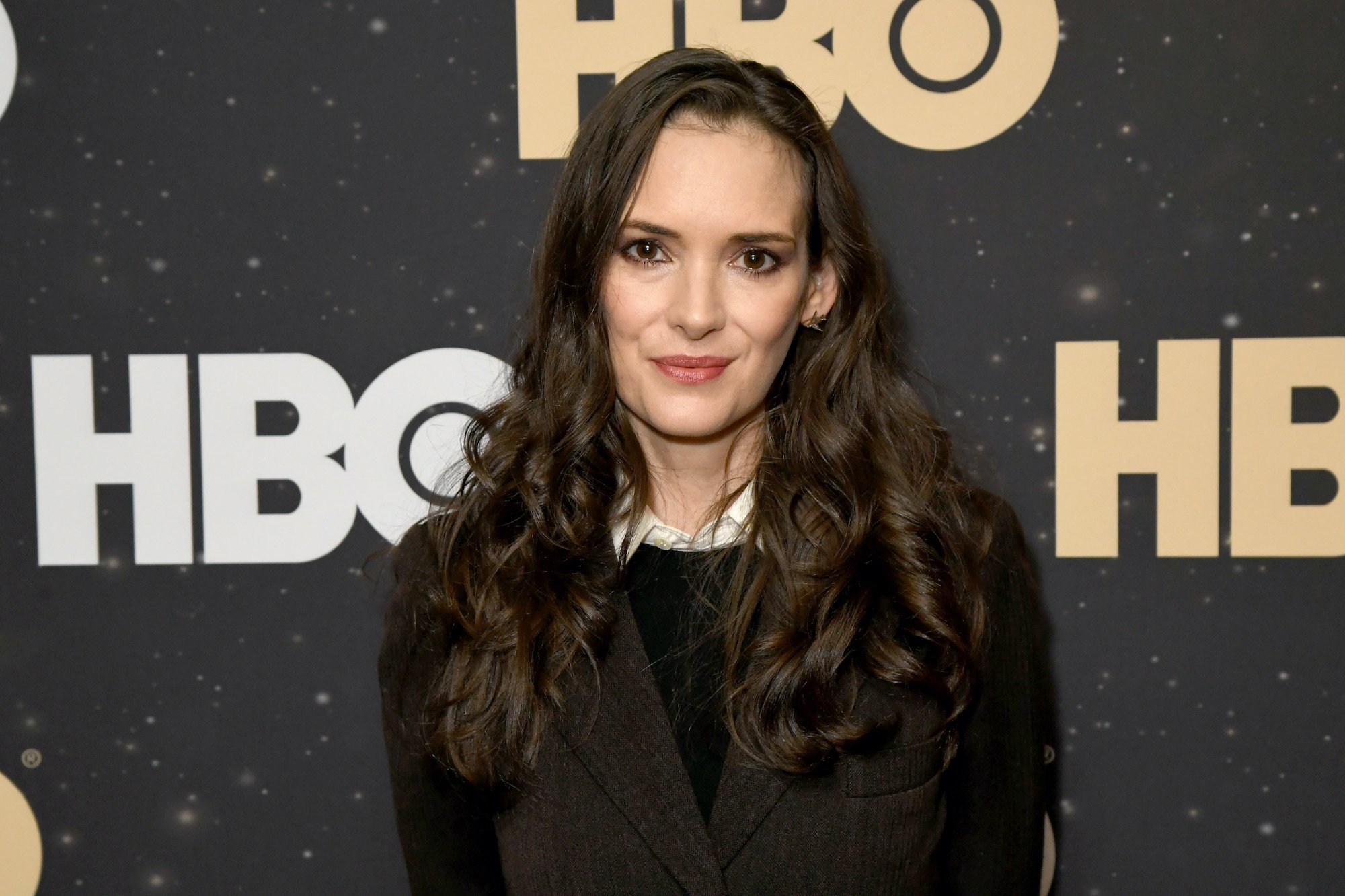 Winona Ryder smiling in front of a black background