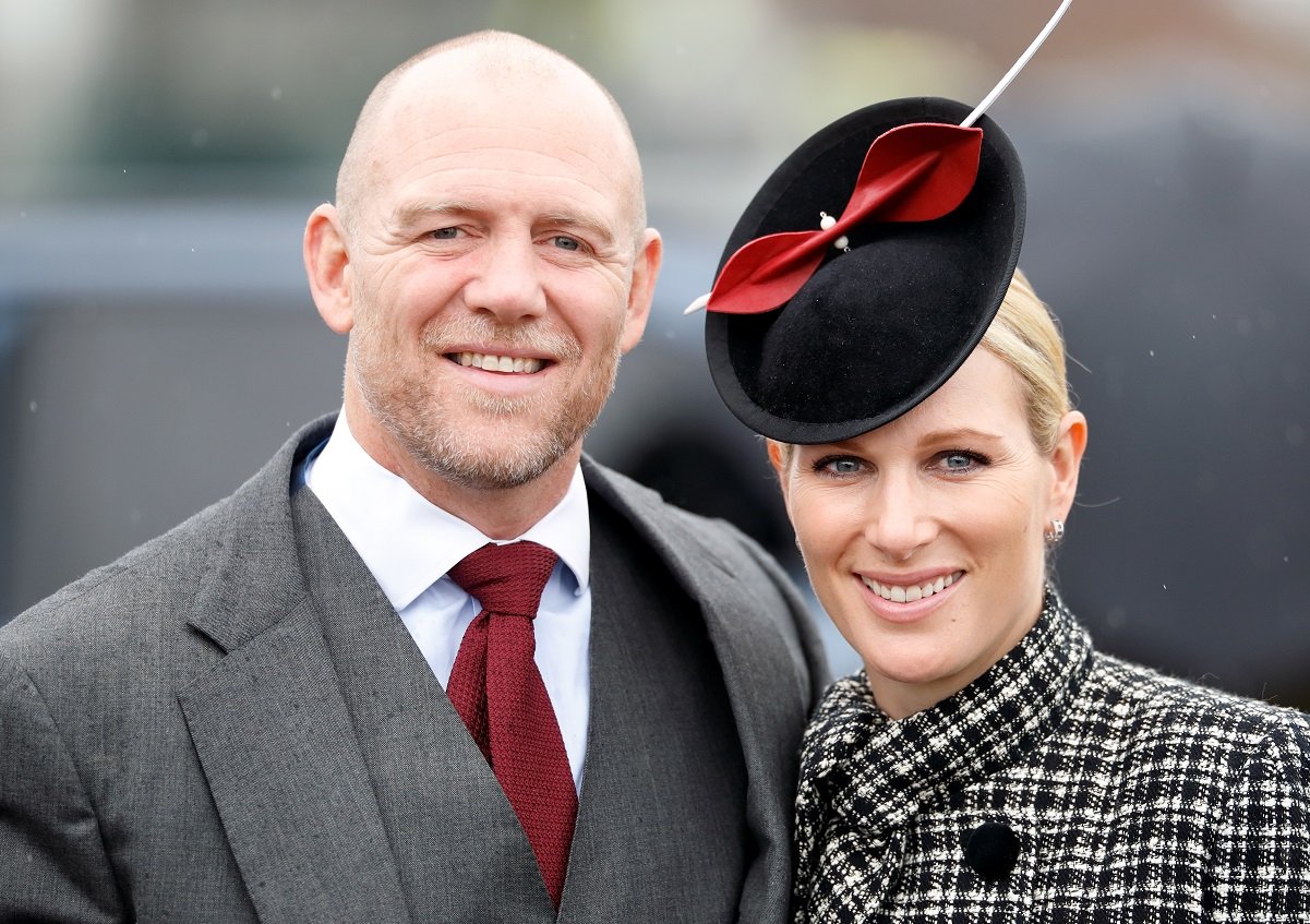 Zara Tindall in a black-white fascinator and Mike Tindall in a suit and red tie pose for a photo together whille attending the Cheltenham Festival at Cheltenham Racecourse