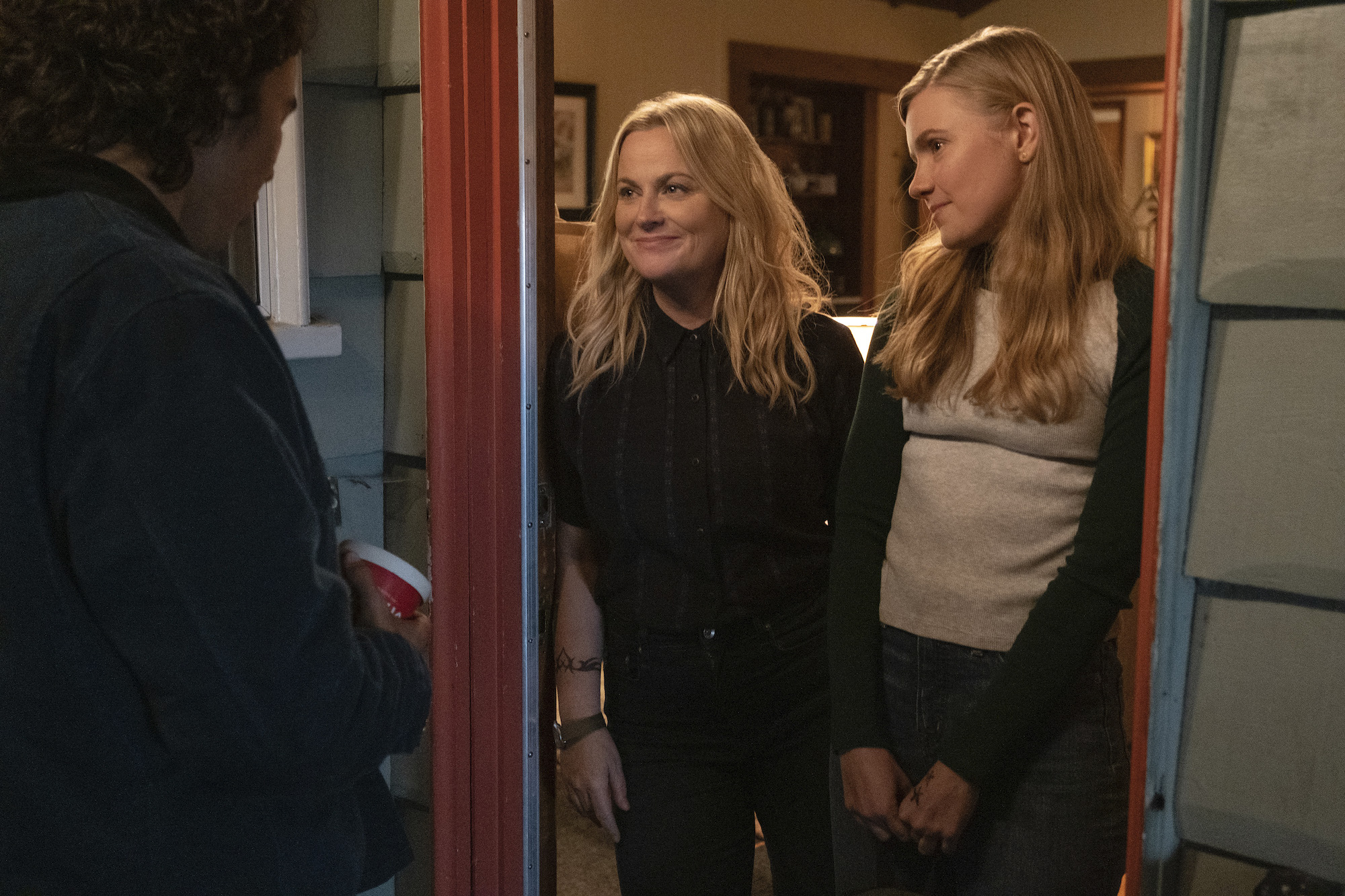 Nico Hiraga as Seth comes to the door as Amy Poehler as Lisa (and Director/Producer) and Hadley Robinson as Vivian answer, 'Moxie' 