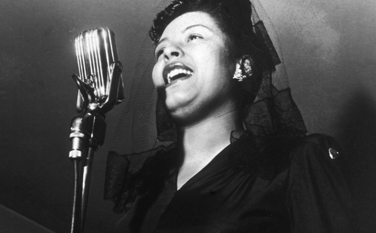 Billie Holiday sings in front of a microphone at a jam session in 1942