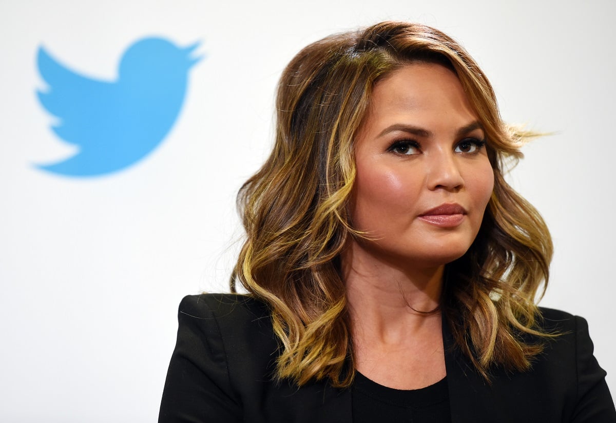 Chrissy Teigen in front of the Twitter logo