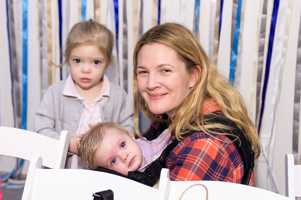 Drew Barrymore holding her daughter, Frankie, while her daughter, Olive, looks at the camera