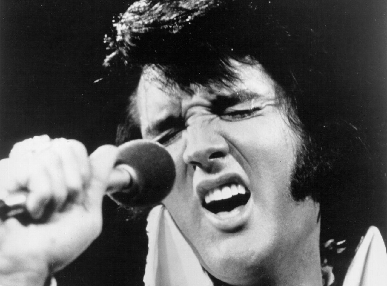 Closeup of Elvis Presley with his eyes closed singing into a microphone