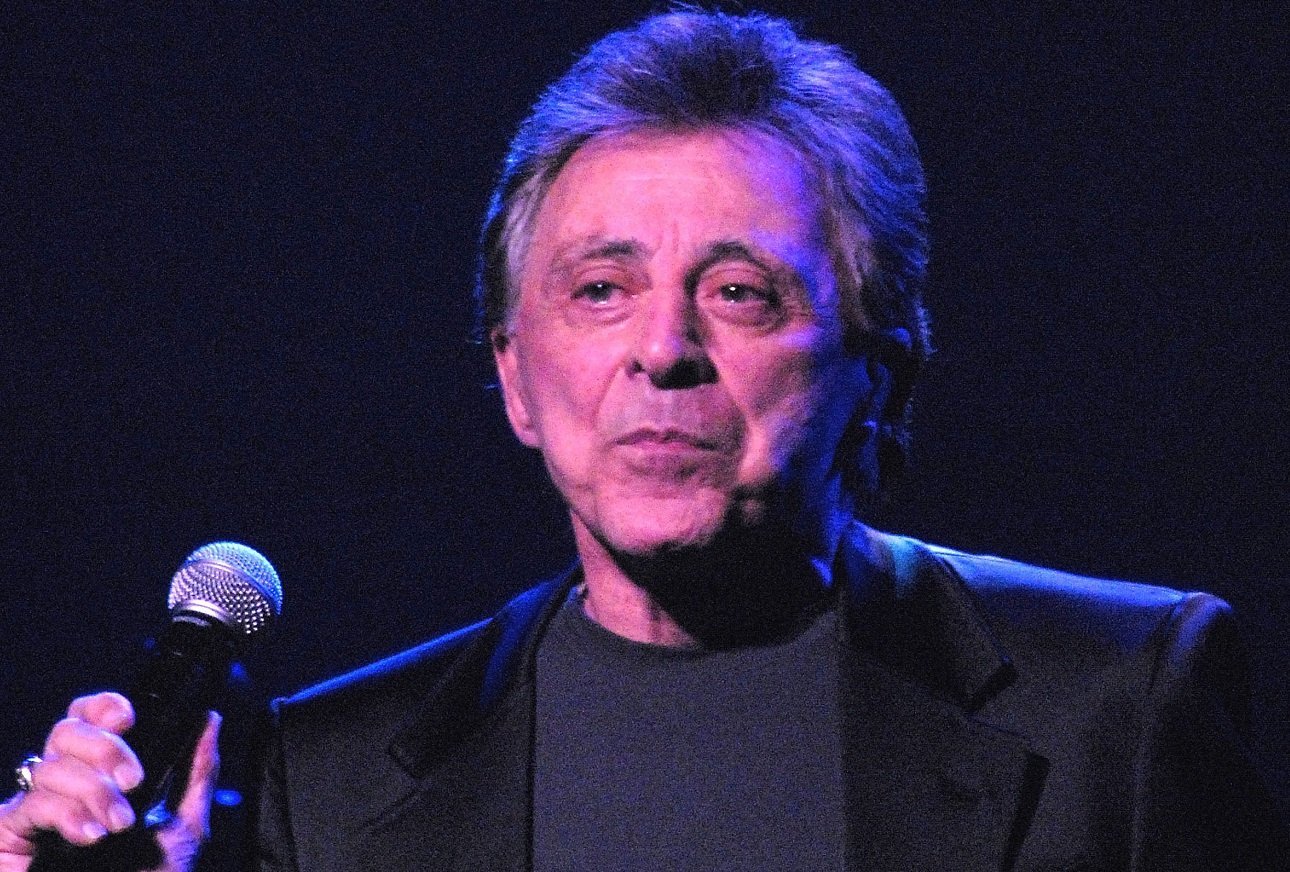 Frankie Valli holds a microphone under the stage lights at Lincoln Center in 2007