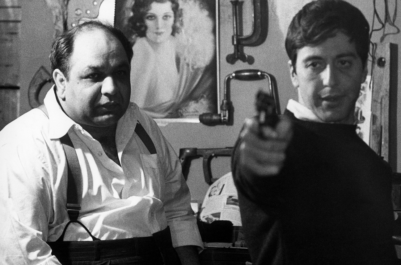 Al Pacino points a gun toward the camera as Richard Castellano looks on in a scene from 'The Godfather'