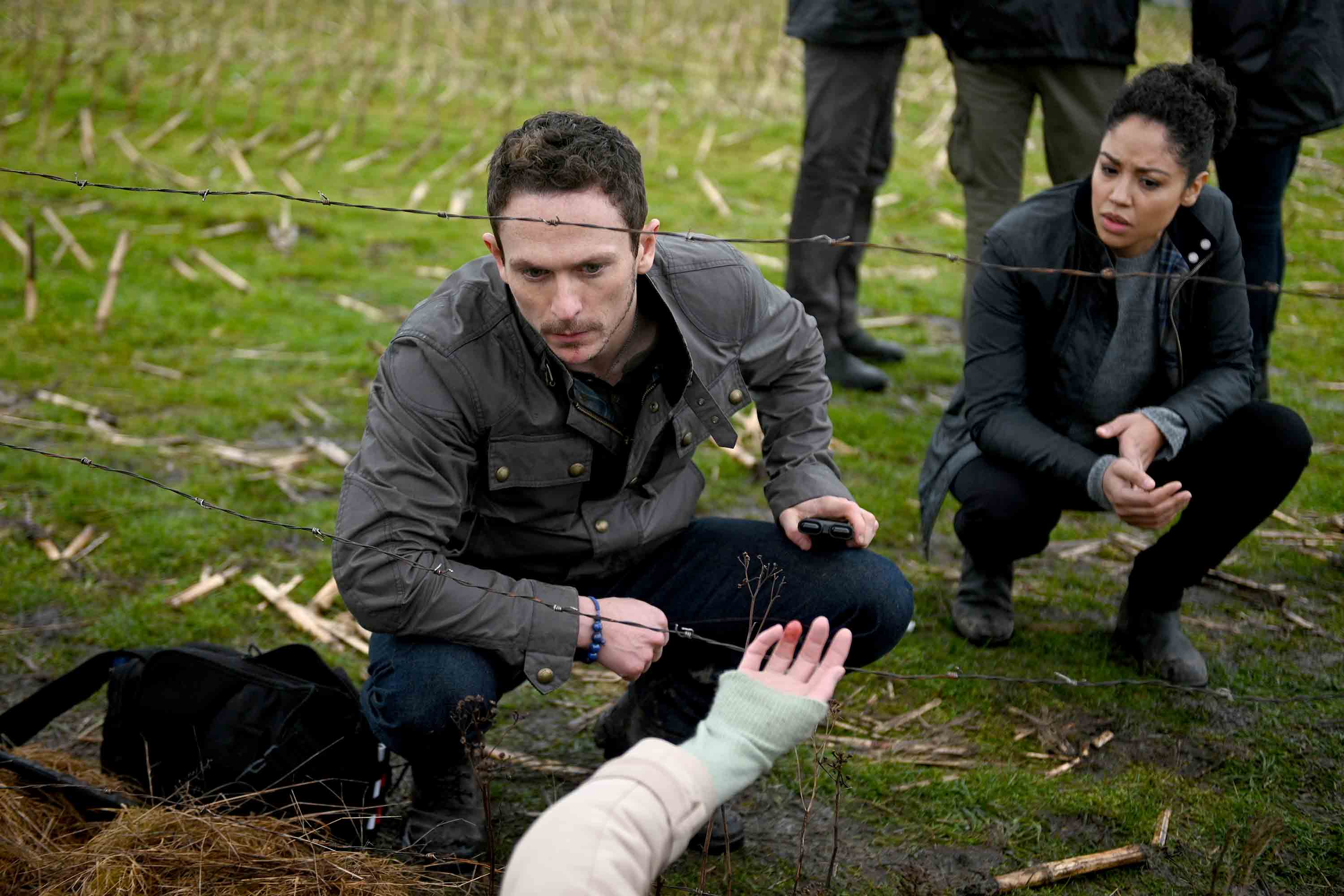 Bryan looks at a hand caught in a fence in Debris series premiere