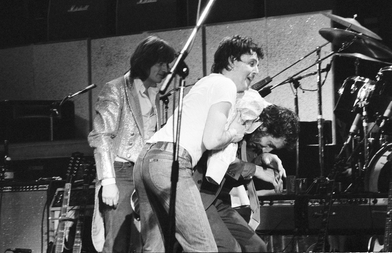 John Paul Jones walks behind Paul McCartney and Pete Townshend, who are joking during a concert rehearsal in 1979
