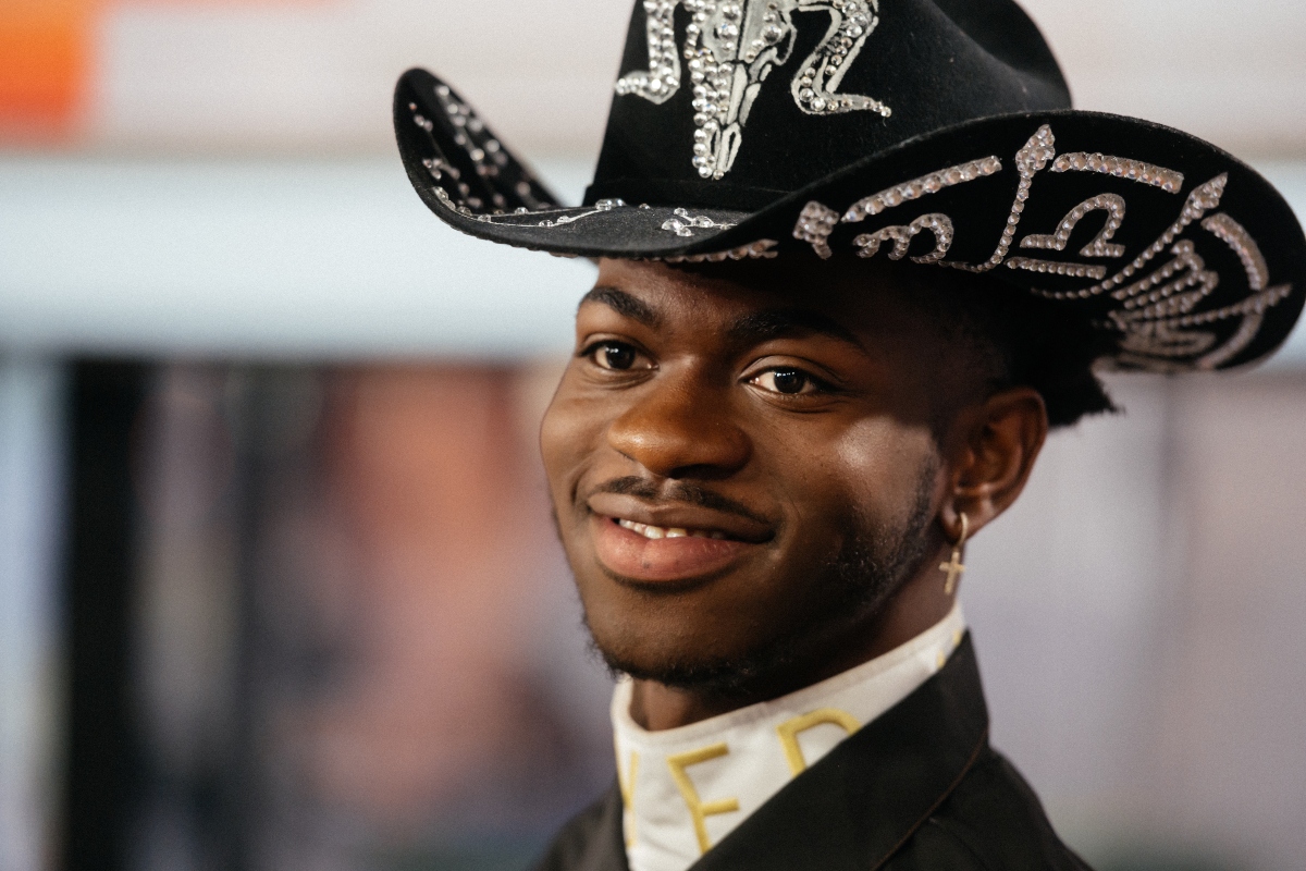 Lil Nas X in a cowboy hat smiling