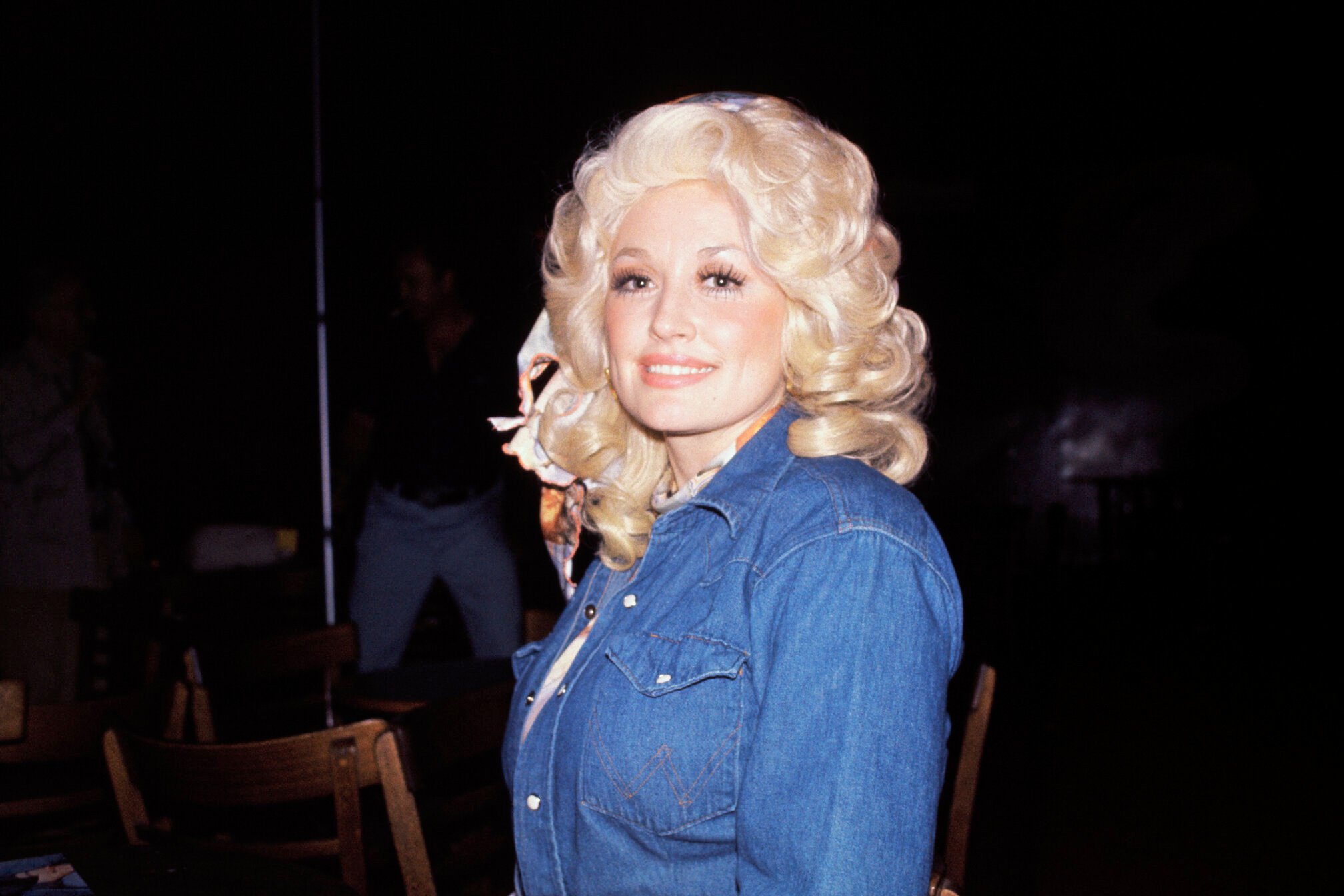 Dolly Parton in a jean shirt with big, curly blond hair.