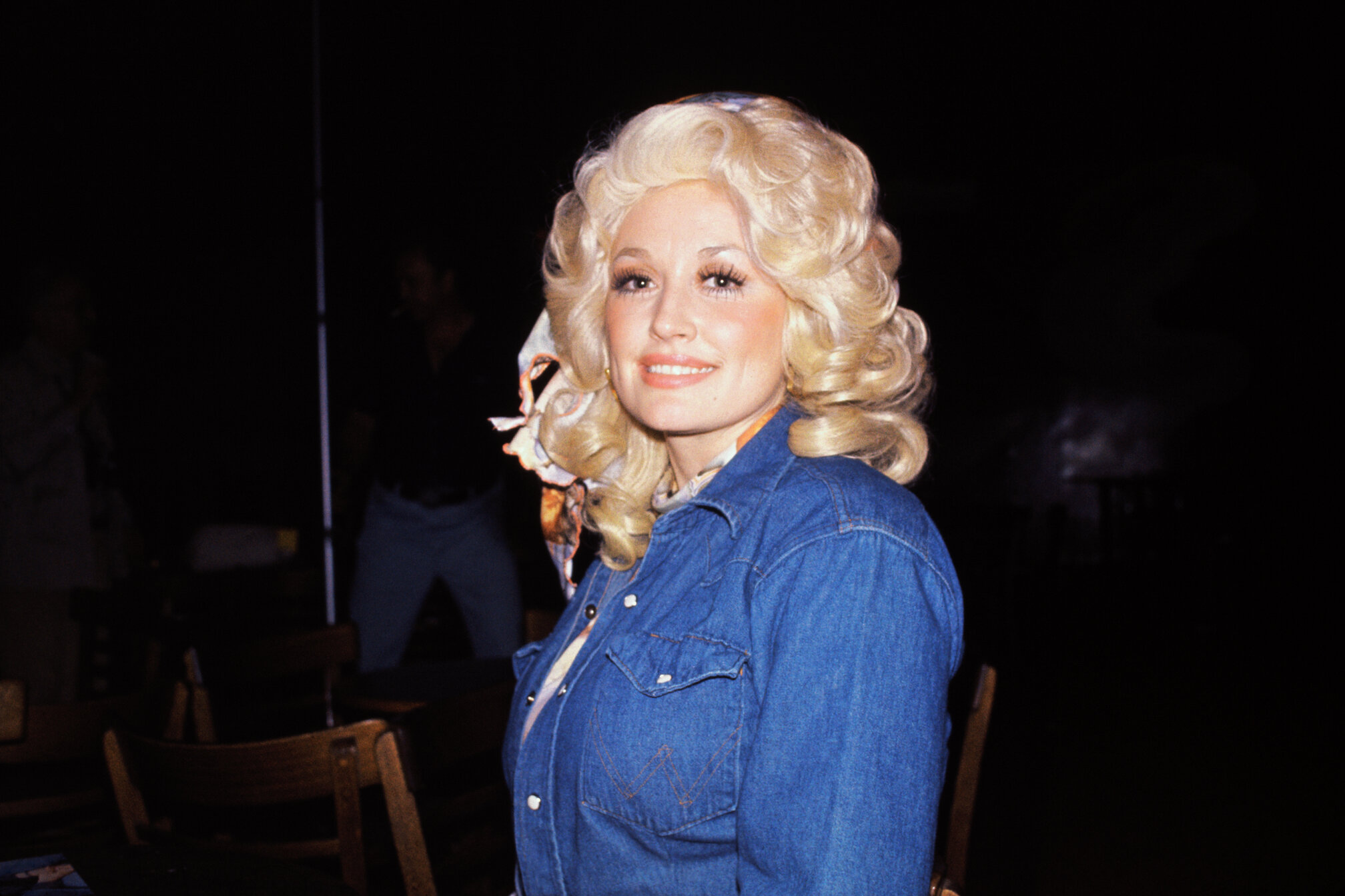 Dolly Parton in a jean shirt with big, curly blond hair.