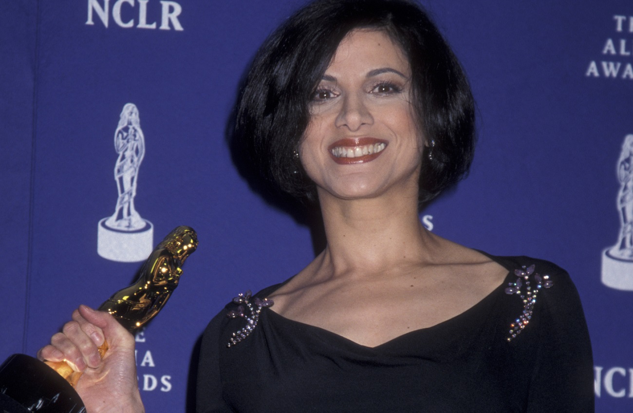 Saundra Santiago smiling and holding an award statuette in 2001