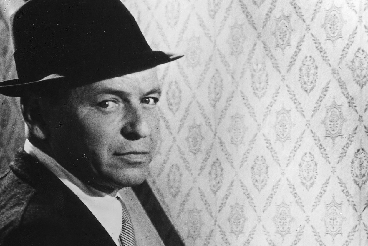 Frank Sinatra, wearing a dark suit and hat, looks at the camera on the 1968 shoot of 'The Detective'