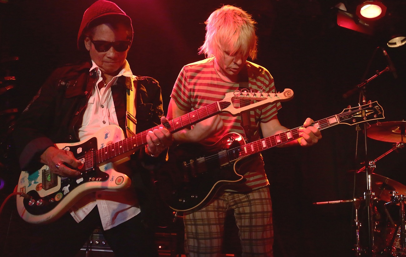 Tony Chin and Zak Starkey playing guitar on stage in 2016