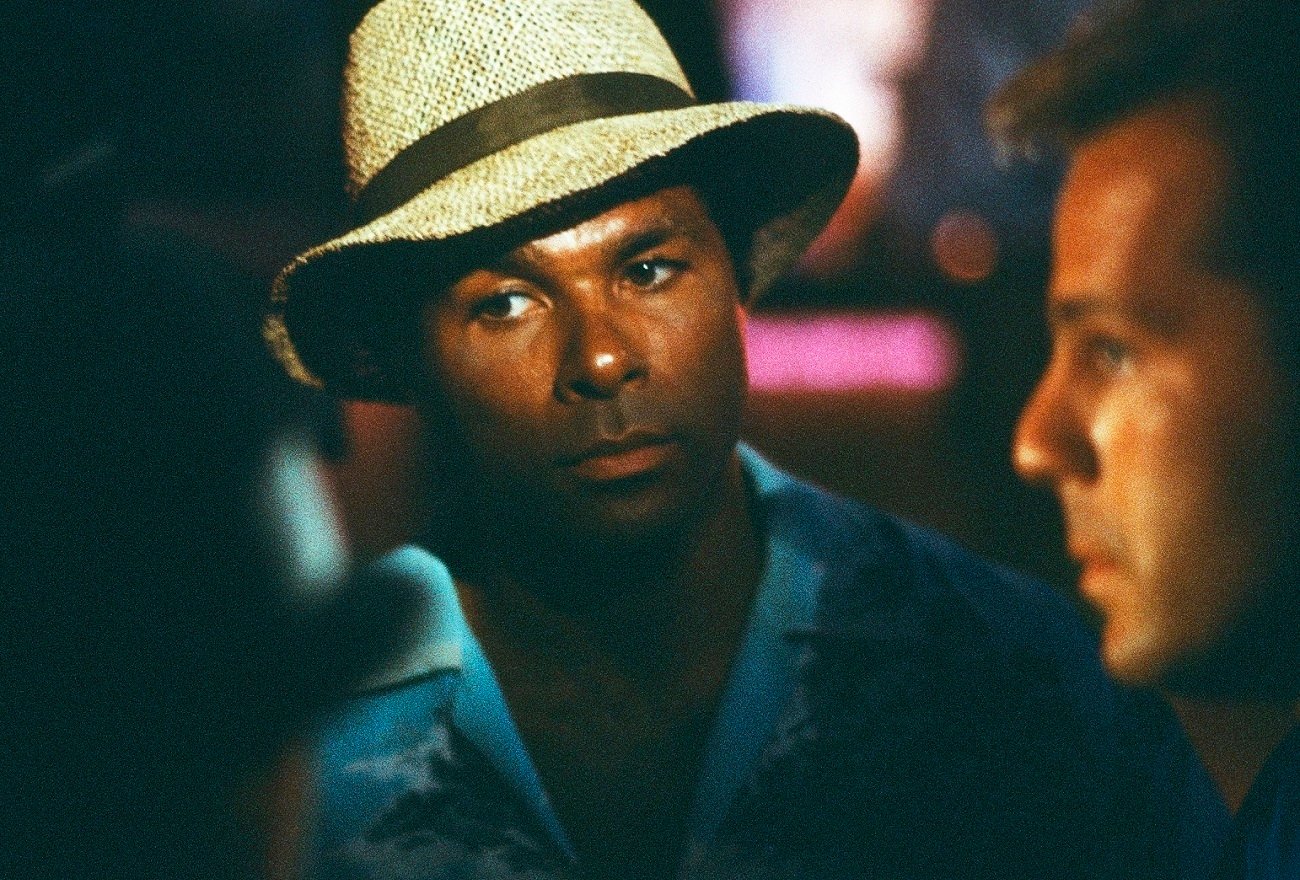 Philip Michael Thomas wears a straw hat as undercover Detective Ricardo Tubbs, Bruce Willis stands out of the light to his left as Tony Amato on 'Miami Vice'