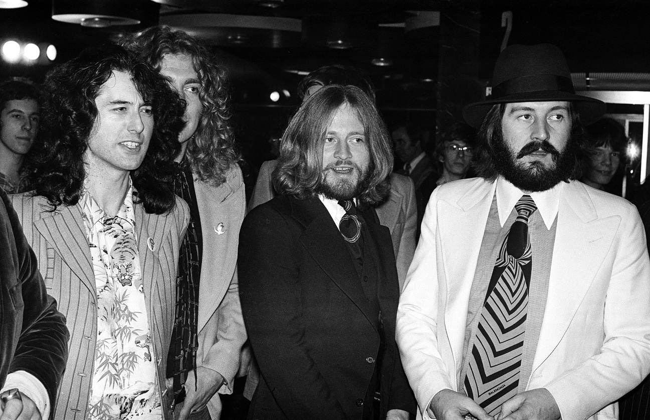 Members of Led Zeppelin look off-camera at a film premiere