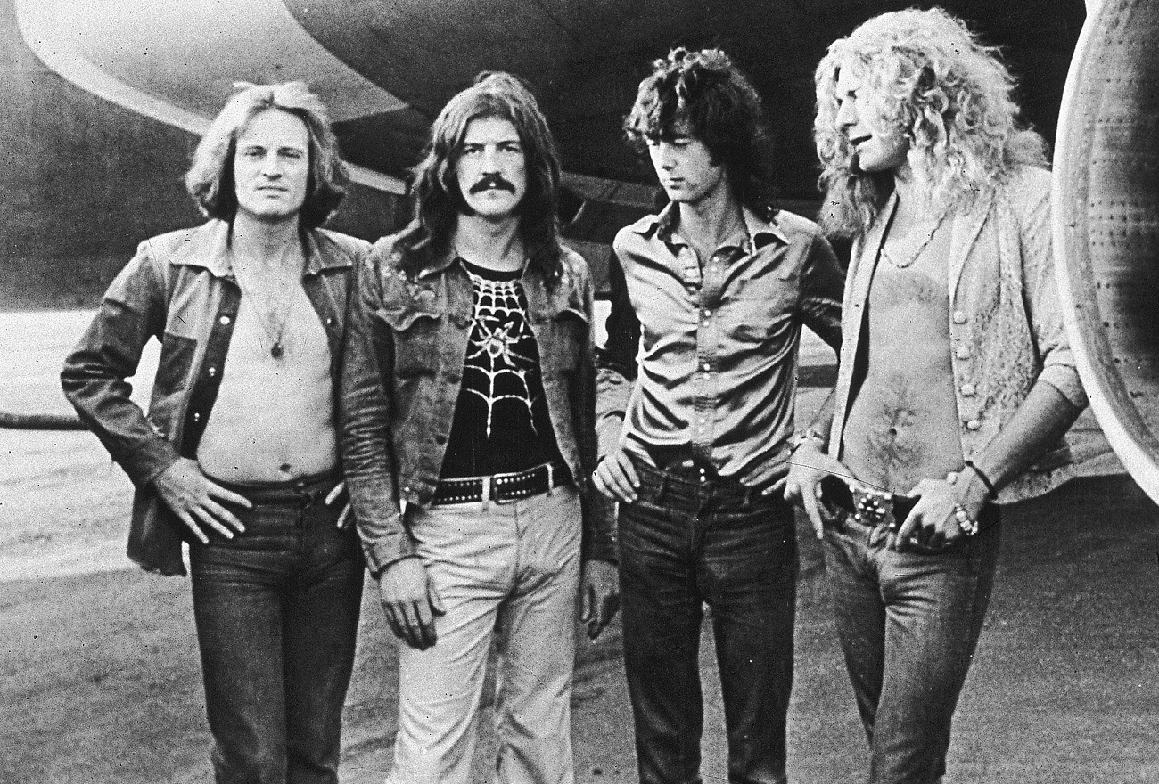 Led Zeppelin posing in front of the engine of the band's private plane