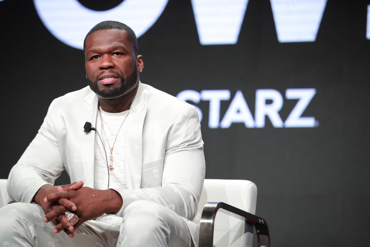 Curtis "50 Cent" Jackson siting on stage wearing a white suit