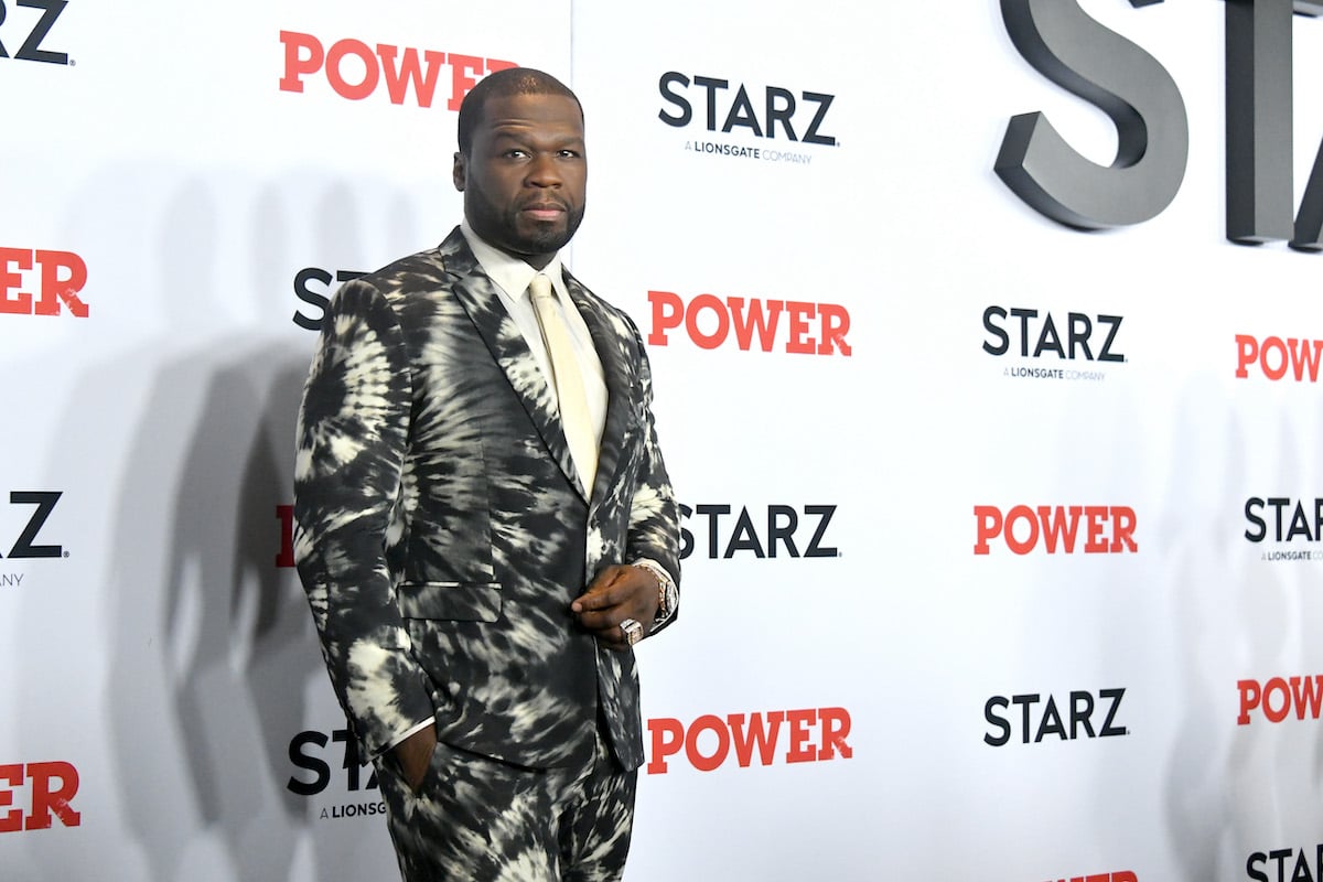 Curtis "50 Cent" Jackson in a black and cream suit standing on a red carpet