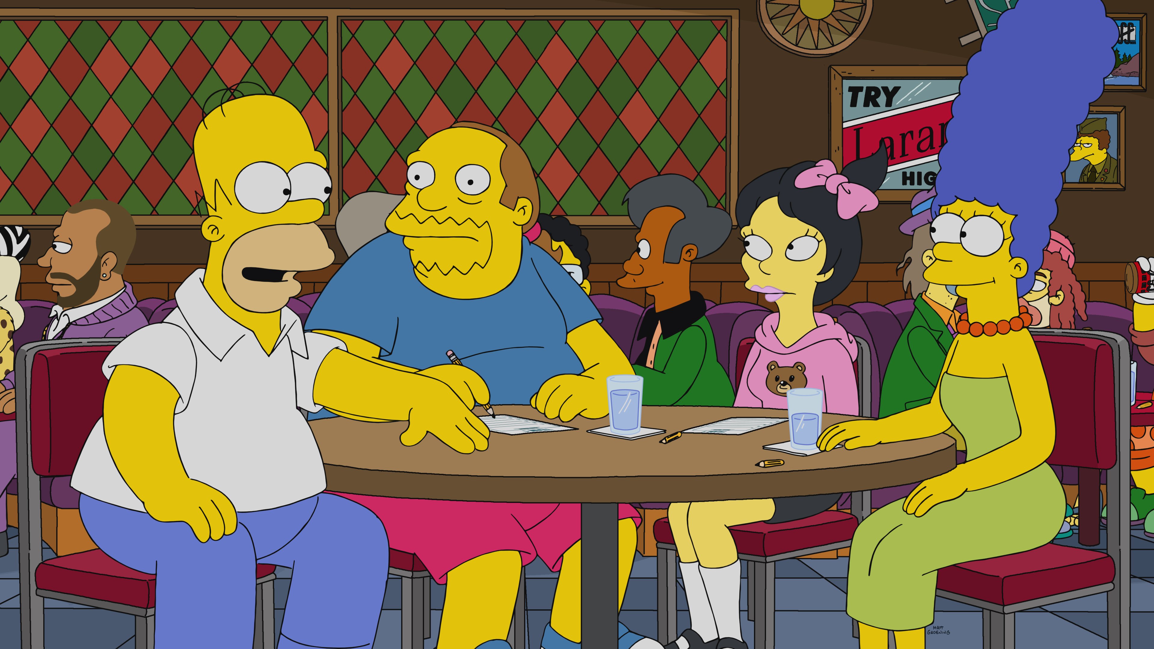 Apu sits behind The Simpsons