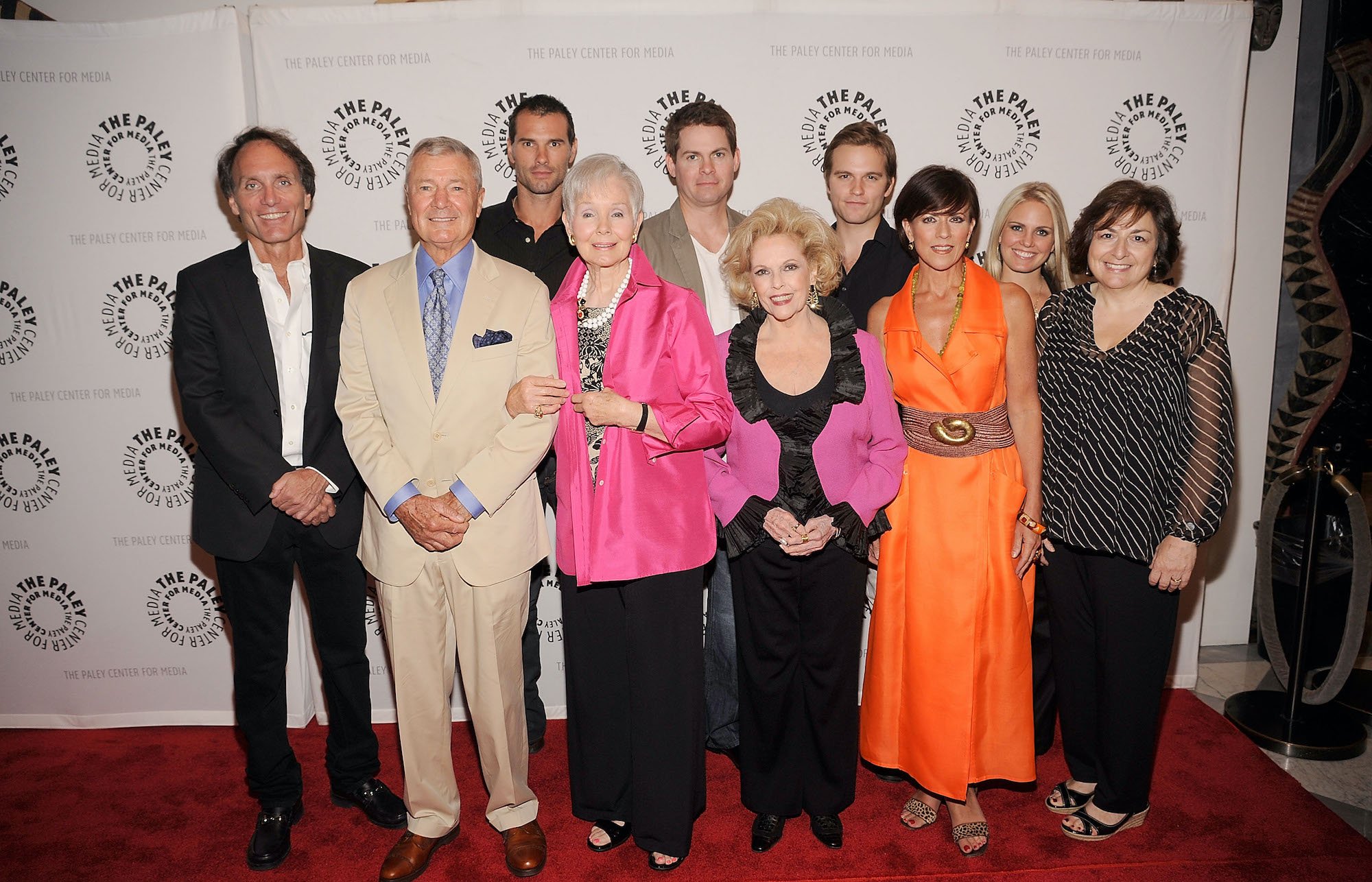 'As the World Turns' cast and creative team smiling in front of a white backdrop on the red carpet