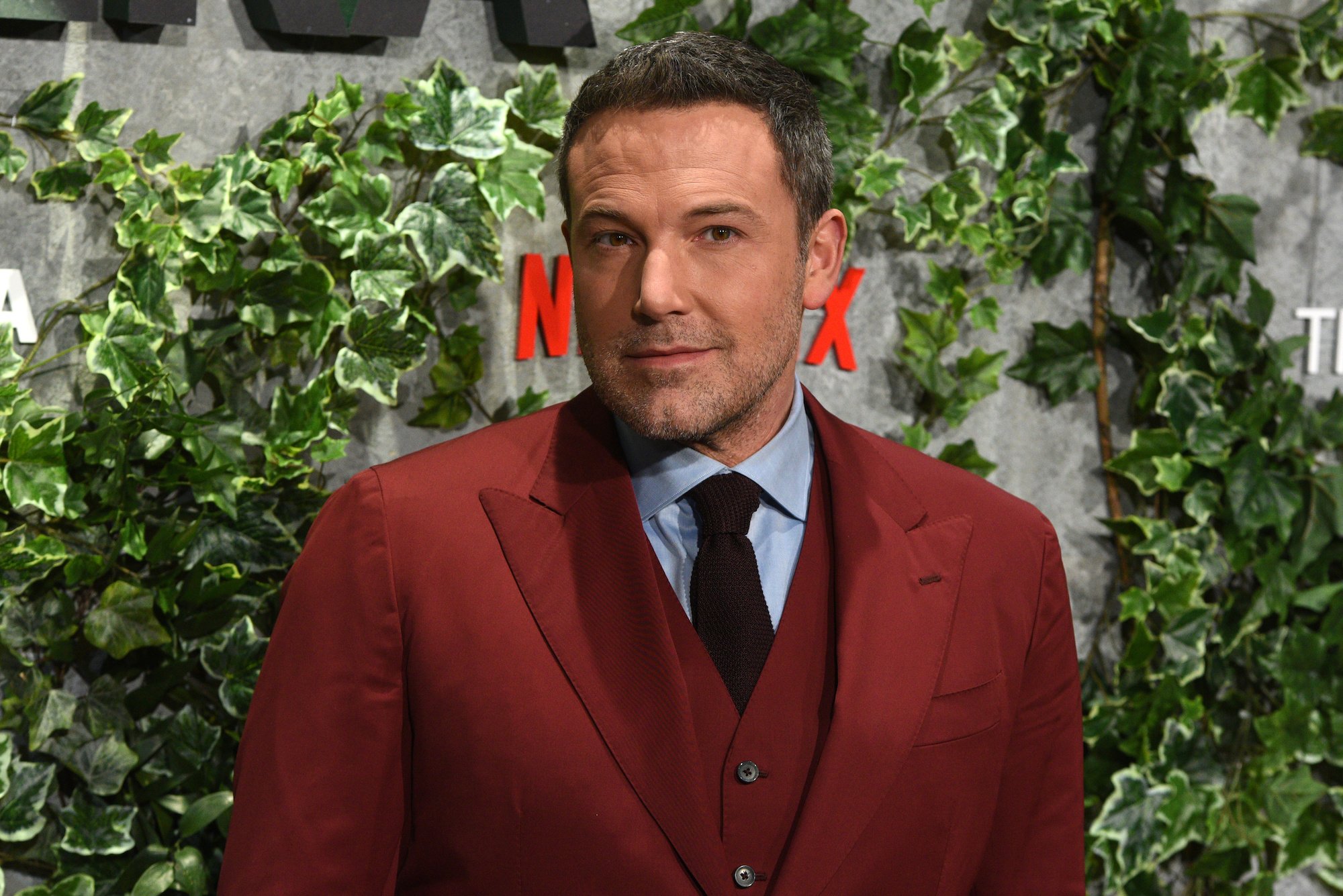 Ben Affleck smiling in front of a green background