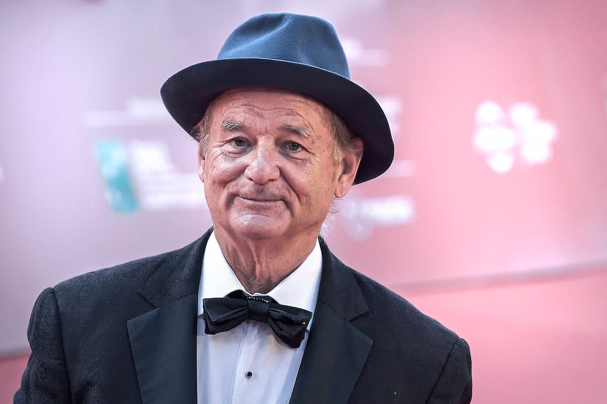 Bill Murray in a black suit and black hat in front of a pink background at the Rome Film Fest 2019