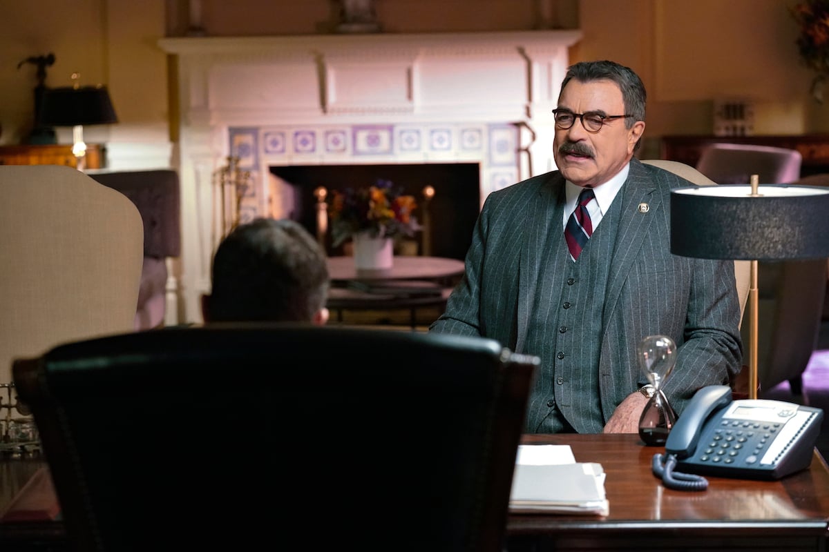 Tom Selleck as Frank Reagan sits in a chair talking to someone in an office on 'Blue Bloods'