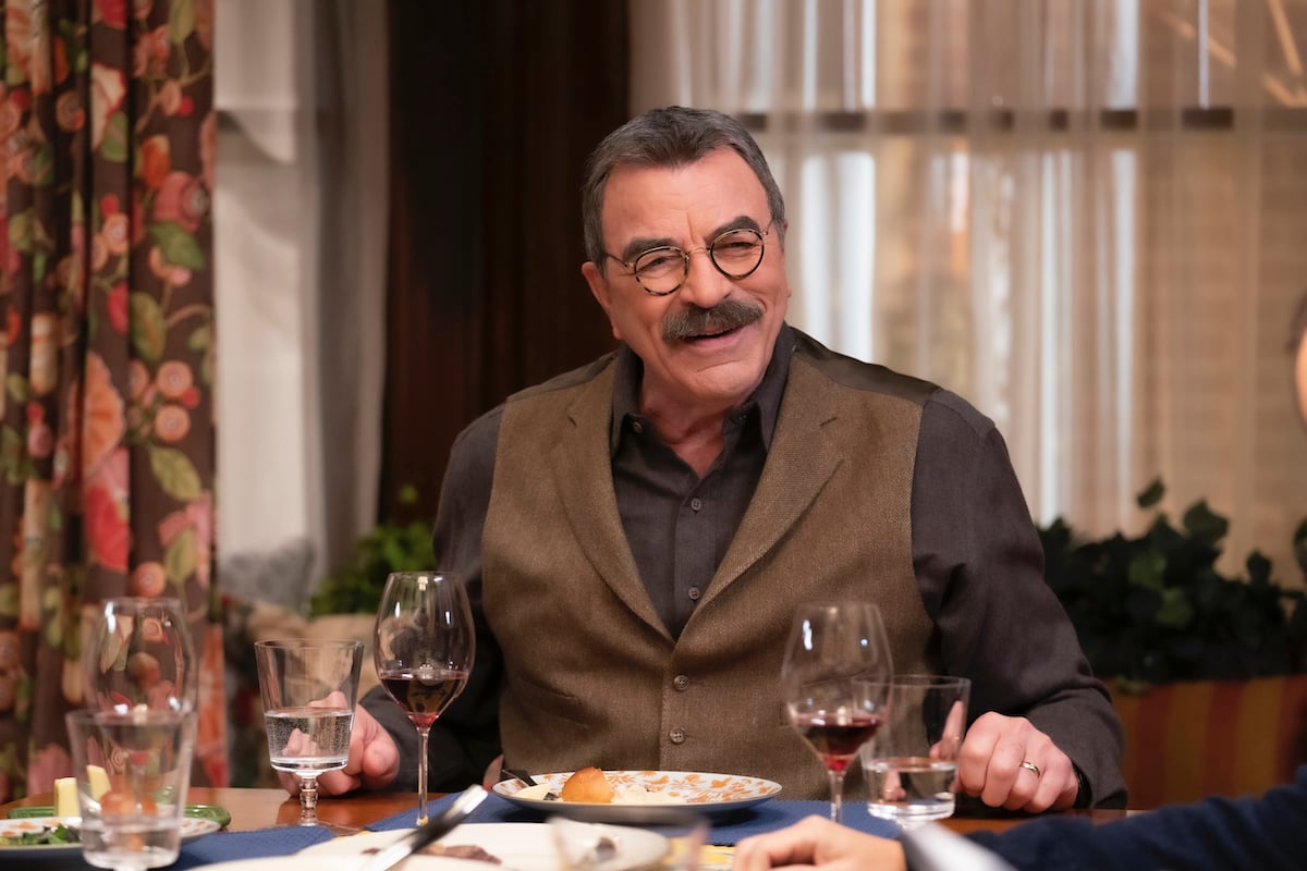 Tom Selleck as Frank Reagan smiles at the dinner table on 'Blue Bloods'