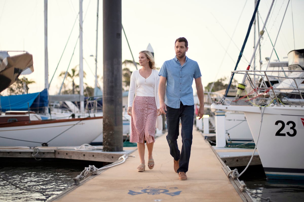 Cindy Busby and Tim Ross walk on a pier in a scene from Hearts Down Under