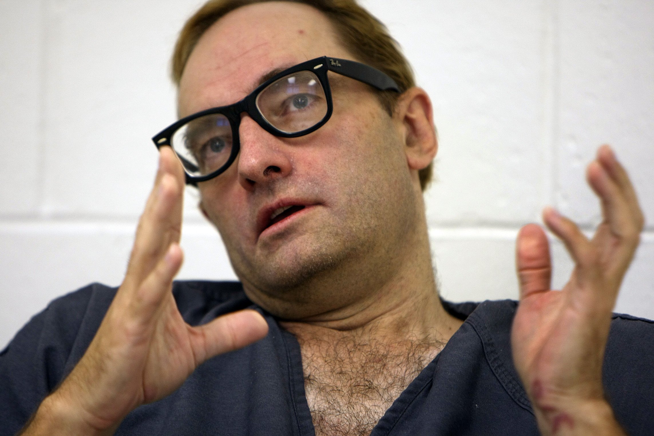 Photo of Clark Rockefeller wearing dark-framed glasses and gesturing with his hands