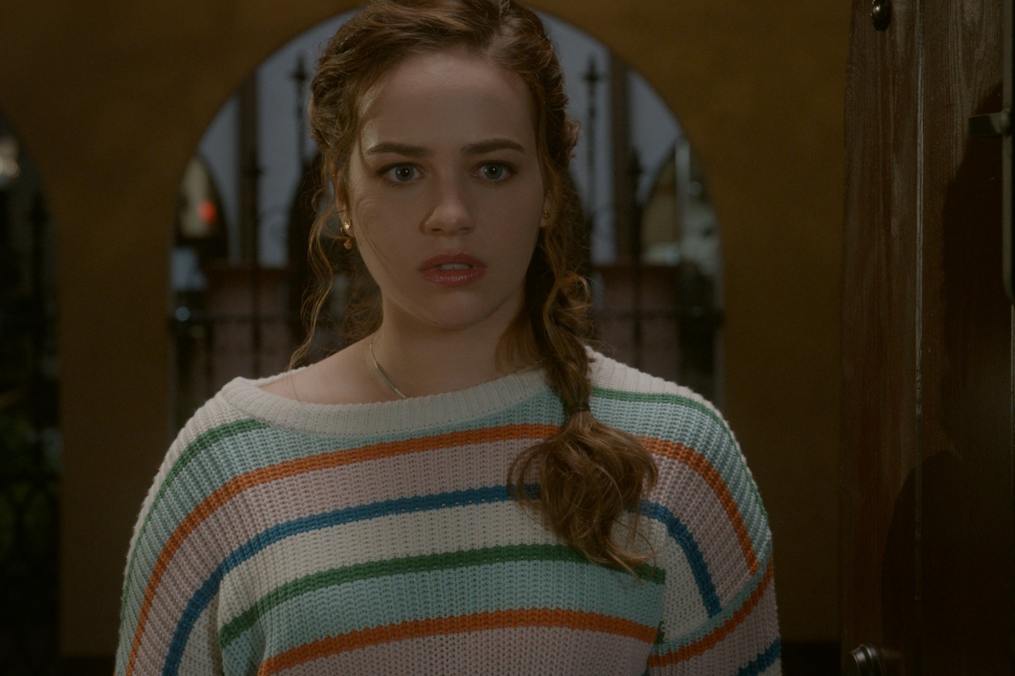 Cobra Kai star Mary Mouser in a blue and pink striped sweater