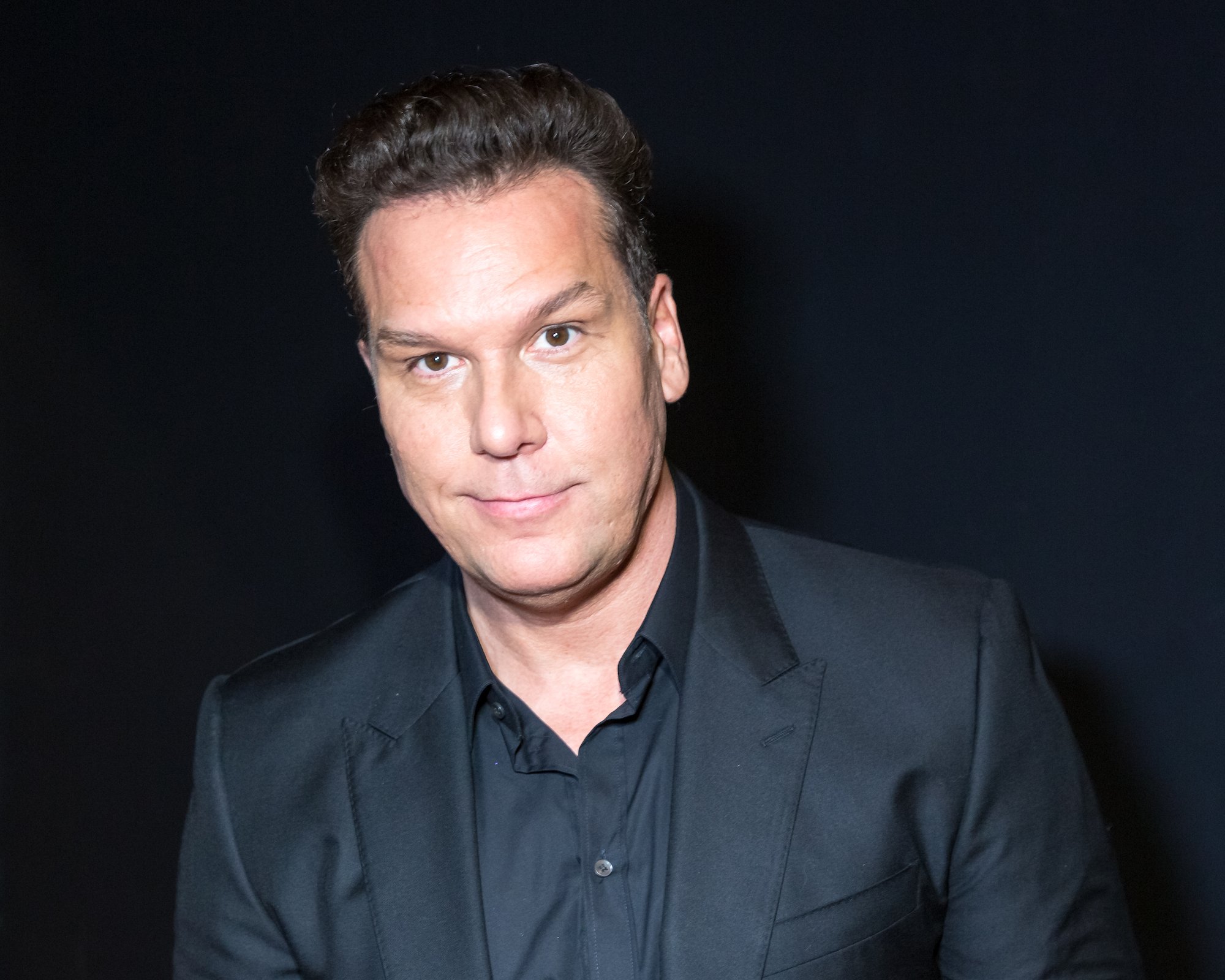 What happened to comedian Dane Cook? Pictured here is Cook smiling in front of a black background