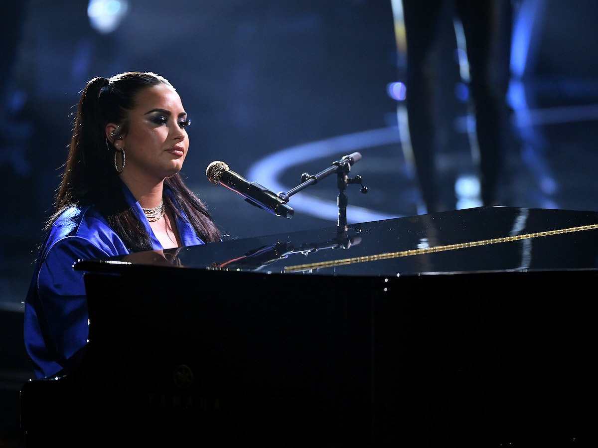 Demi Lovato sits at a piano ready to sing