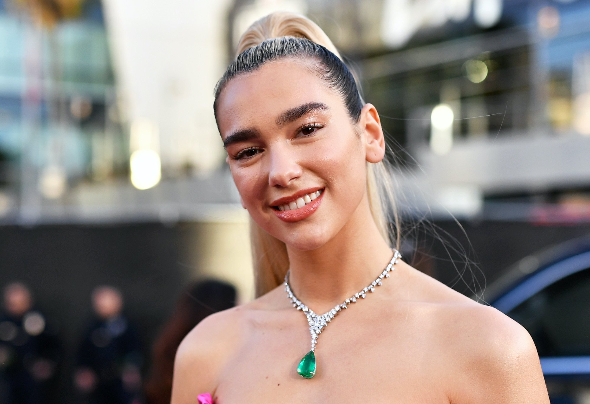 Dua Lipa smiling in front of a blurred background