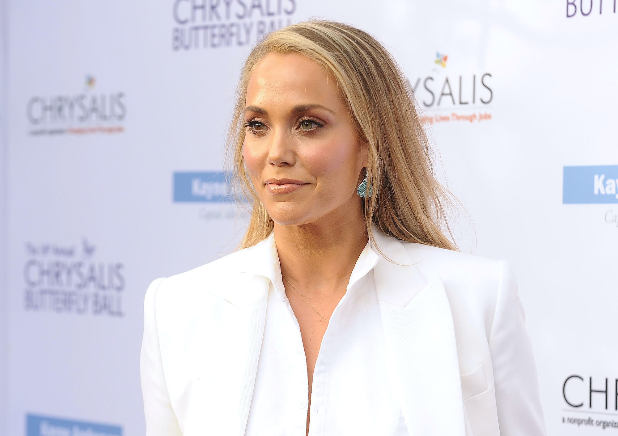 Elizabeth Berkley smiling in front of a white background