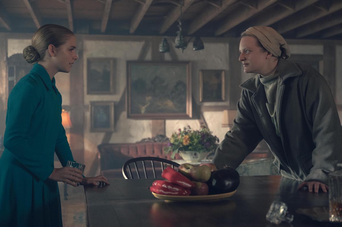 Mckenna Grace as Mrs. Esther Keyes in a teal dress (L) and Elisabeth Moss as June Osborne in a grey coat (R) in 'The Handmaid's Tale' Season 4