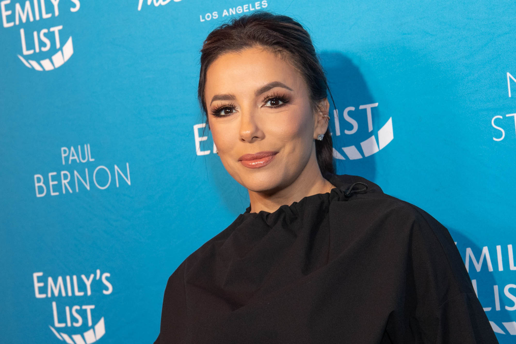 Eva Longoria smiling in front of a blue background