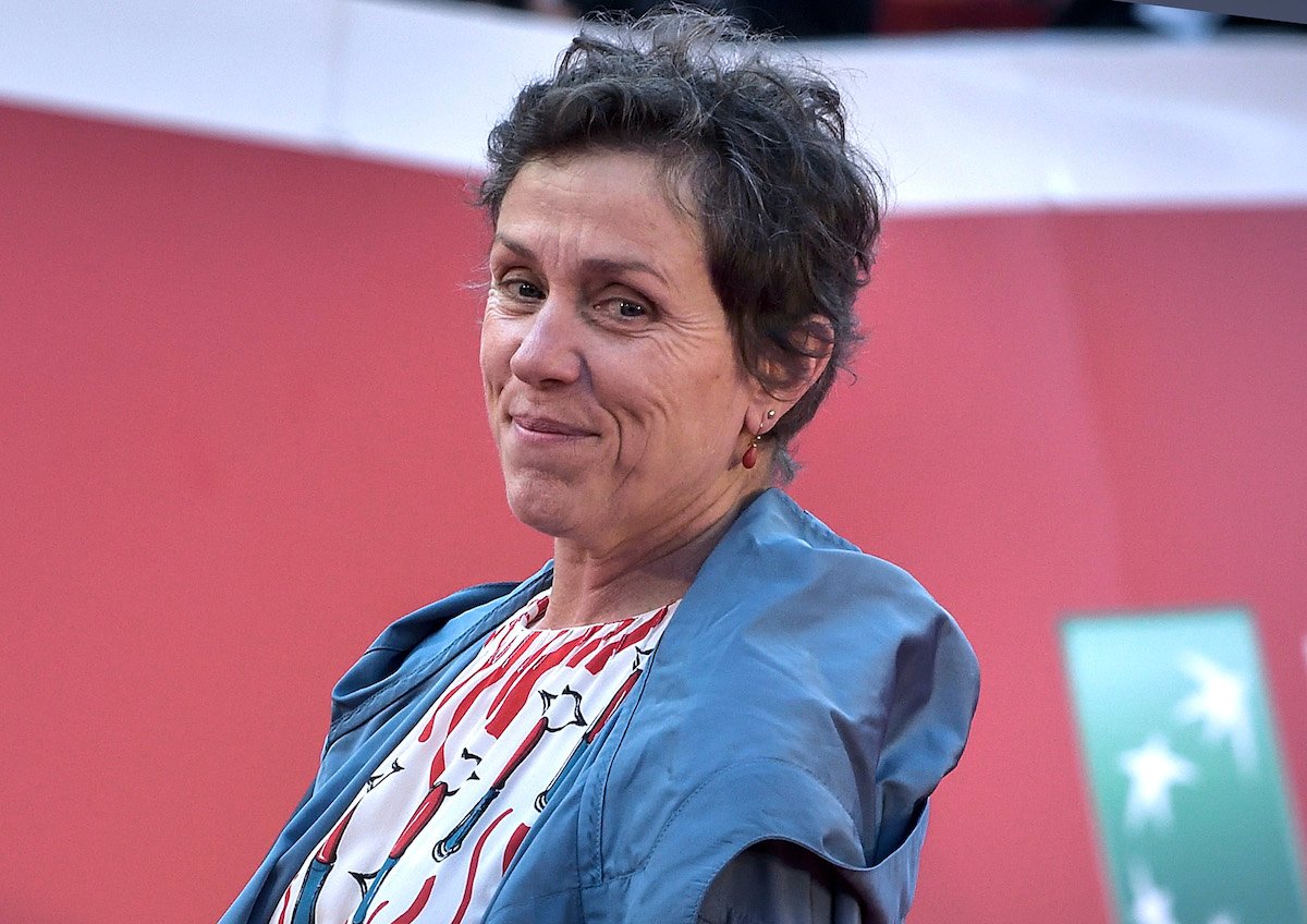 Frances McDormand smiles in a blue coat on the red carpet of Rome Film Fest 2019