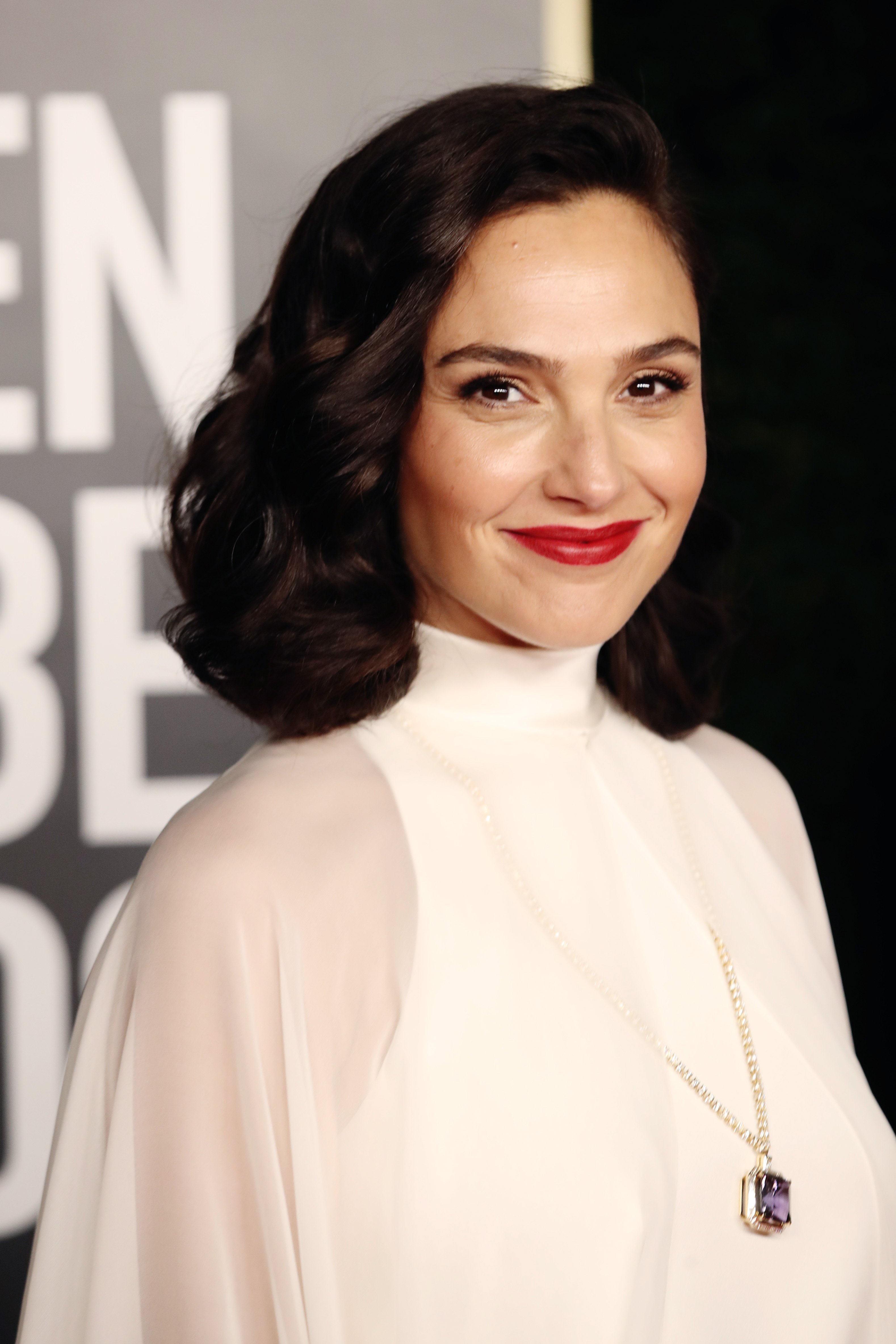 Gal Gadot smiling in a white gown at the 78th Annual Golden Globe Awards